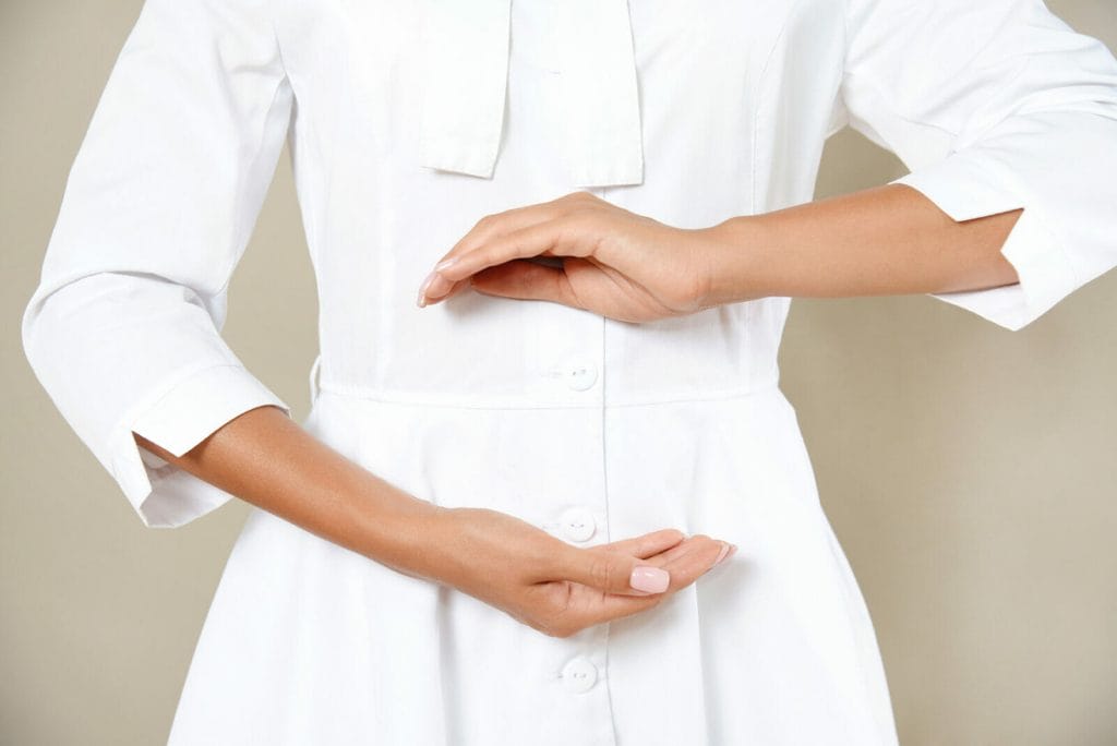 Close up cropped photo of woman's slim stomach with her hands showing a balance in microflora in a white robe. Healthy eating concept.